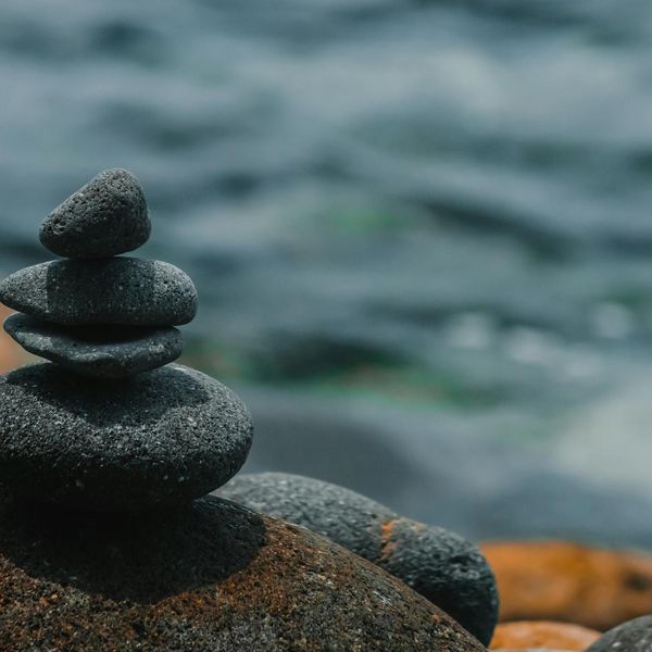 A balanced stack of smooth stones against a calm ocean background, symbolizing stability.