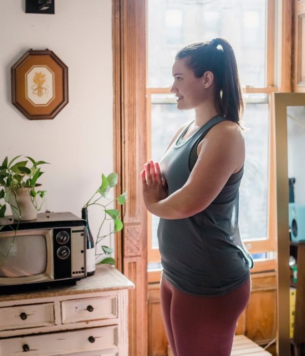 Woman practicing a peaceful yoga pose in a room with abstract wave decor.